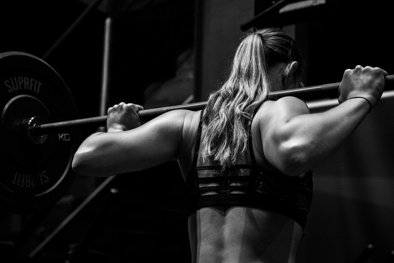Woman strength training with a barbell in a gym