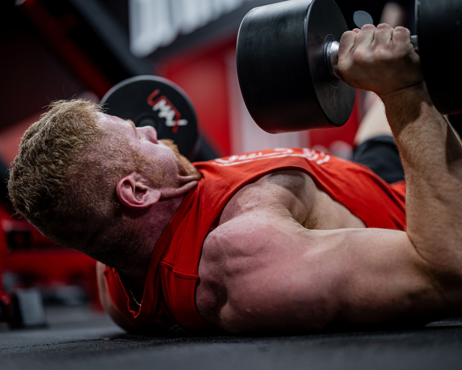 Athlete training with dumbbells and a workout log for progressive overload
