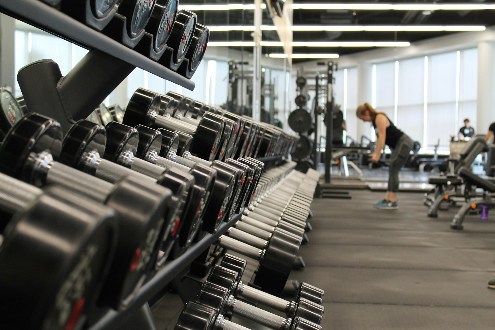 Coach supporting safe strength training technique in a gym